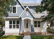 Charming blue bungalow home features concrete steps leading to a blue portico illuminated by an iron lantern hung in front of a glass panel white front door.