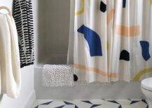 Light gray and blue bath floor tiles add a contemporary appeal to a kid's bathroom featuring a drop-in bathtub with a multi-colored shower curtain.