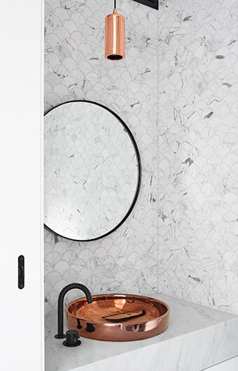 A luxurious bathroom featuring marble-like walls and a copper sink.