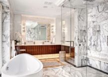 A luxurious bathroom featuring exquisite marble flooring and a spacious tub flanked by a wooden vanity.