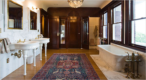 A spacious bathroom with a plush rug and a white bathtub, featuring wood accents.