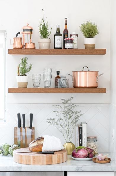 Rustic kitchen with floating shelves that stocks glassware, pots, and jam.