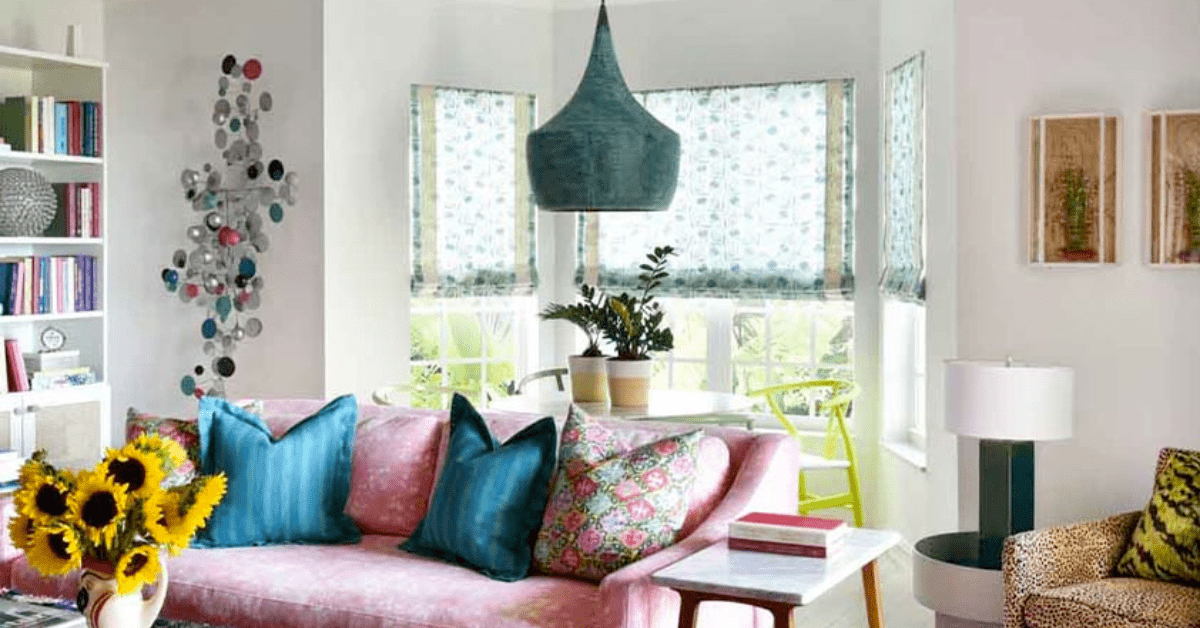Pink couch flanked by bay window curtains with patterns.
