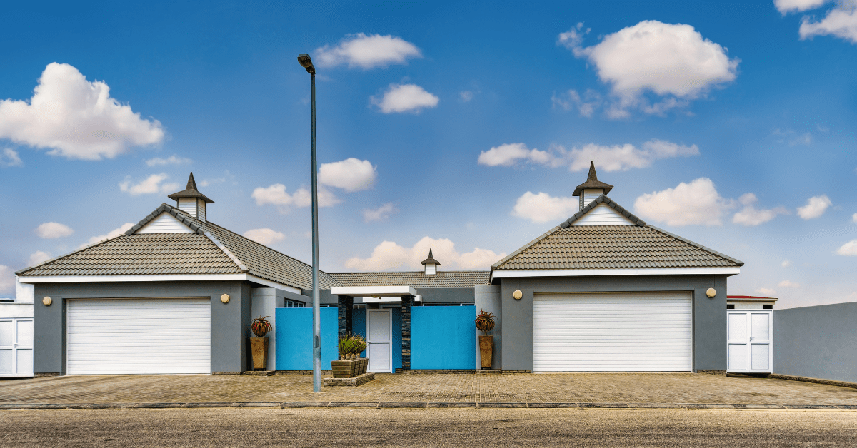 Exterior of a duplex with garages flanked by clear sky.