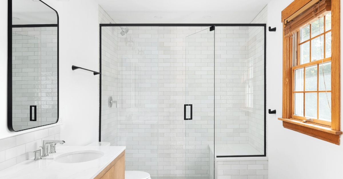 White themed bathroom with a glass shower flanked by subway tile shower.