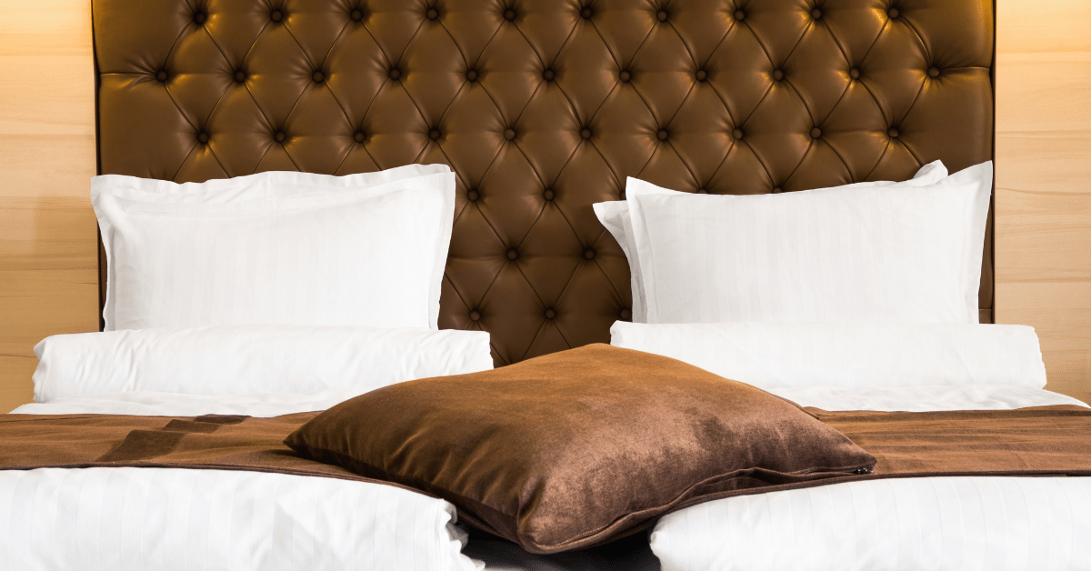 Brown bed with white pillows and sheets.